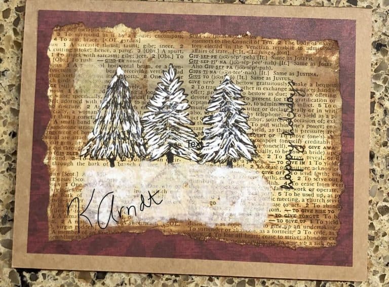 "Merry Christmas to all my friends in this wonderful book club! I wrote my name large on this photo copy. The originals went out unblemished 😂 It’s coffee stained paper, the snow is a paper towel dabbed with white paint. I drew the trees first them applied the snow. The edges are torn because I happen to like that look to make it look aged." Created by Kandice Arndt